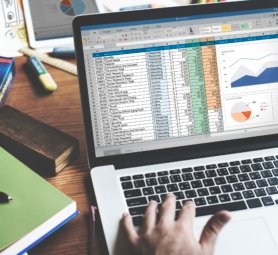 Closeup of hands using computer laptop with screen showing analysis data